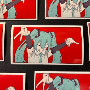 Pode incluir: Autocolantes retangulares com uma personagem de anime com longas tran&ccedil;as turquesa, uma camisa branca e uma gravata azul, sobre um fundo vermelho. A personagem est&aacute; numa pose com os bra&ccedil;os estendidos e os dedos apontando para baixo.