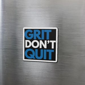 May include: A black and white motivational quote magnet with blue text that reads "GRIT DON'T QUIT".