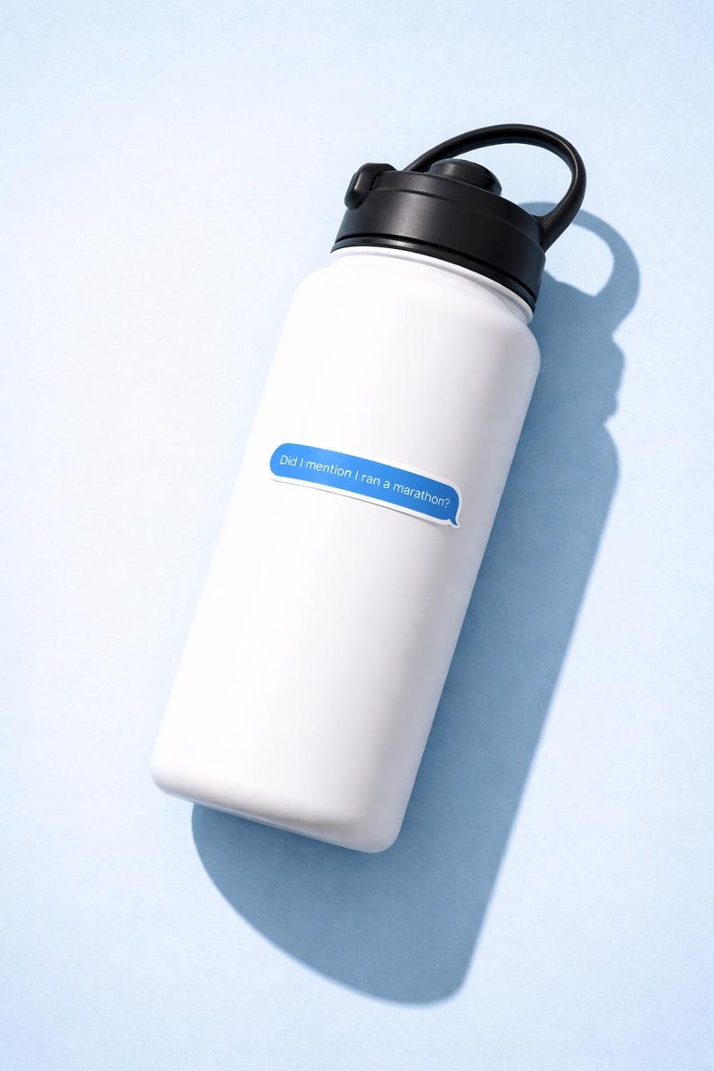 K&ouml;nnte beinhalten: Wei&szlig;e Wasserflasche mit schwarzem Deckel und Griff. Ein blauer Aufkleber auf der Flasche lautet: "Did I mention I ran a marathon?" Die Flasche befindet sich auf einem hellblauen Hintergrund.