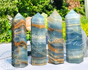 Könnte beinhalten: Vier blaue und braune gebänderte Achat-Kristallspitzen, auch bekannt als gebänderter Onyx, in einer Reihe auf einer hellbraunen Holzoberfläche angeordnet. Die Spitzen sind etwa 10 cm hoch.