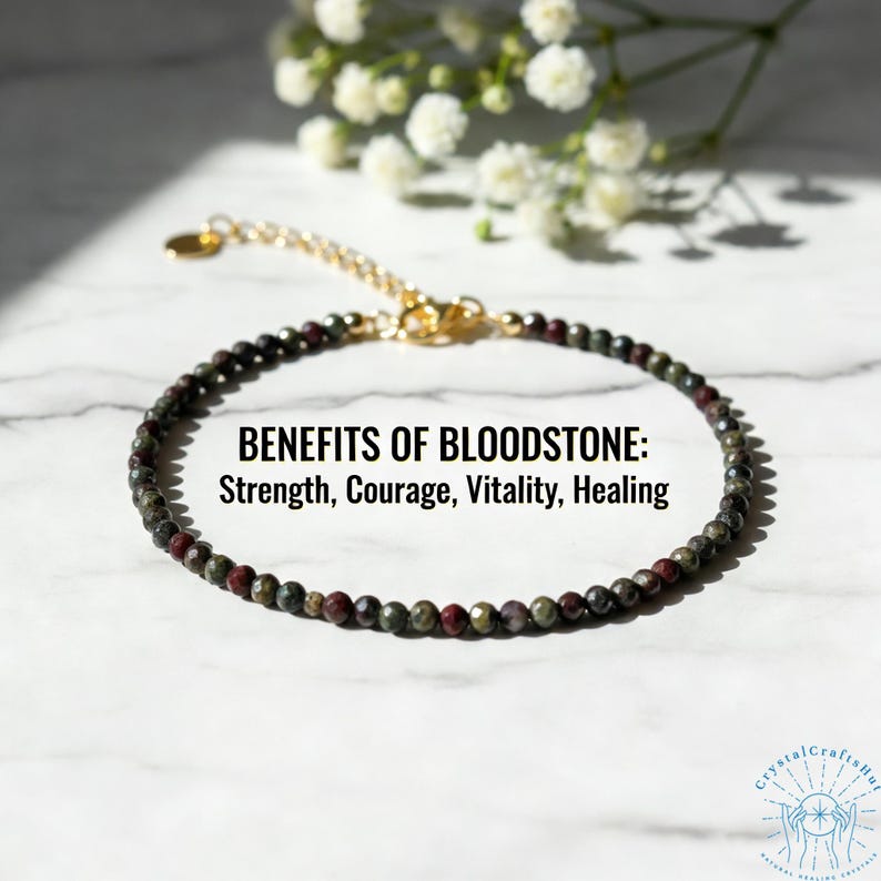May include: A beaded bloodstone bracelet with a gold-colored chain and clasp. The bracelet features small, round beads in shades of green and red. Text on the image reads: BENEFITS OF BLOODSTONE: Strength, Courage, Vitality, Healing.