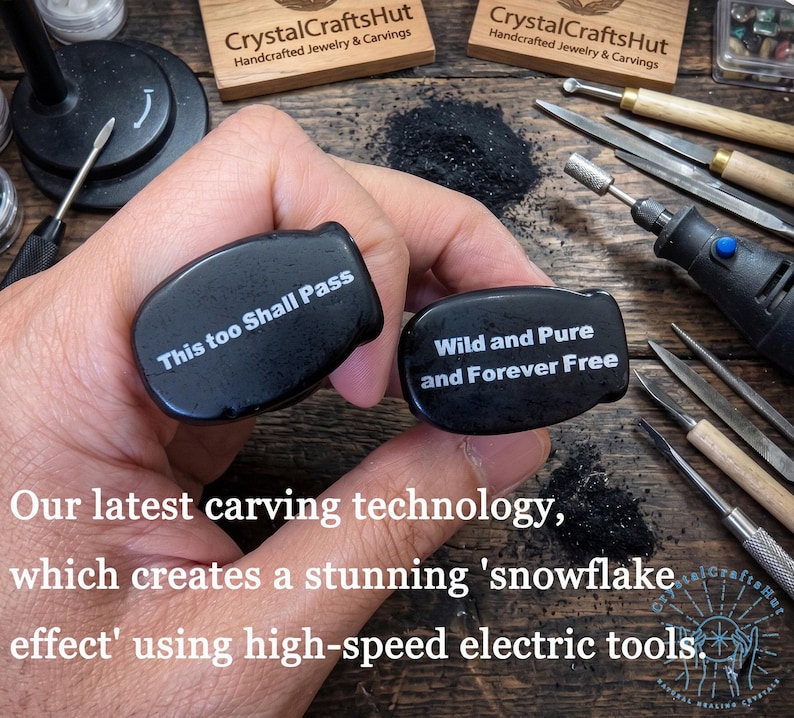 May include: Two black, oval-shaped carvings with white text reading "This too Shall Pass" and "Wild and Pure and Forever Free." The carvings are held near carving tools and a rotary tool. The image shows the CrystalCraftsHut logo.