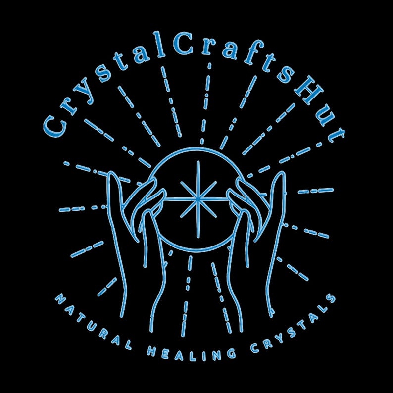 May include: A blue line drawing of two hands holding a crystal ball with a star inside. The text "Crystal Crafts Hut" is above the hands and "NATURAL HEALING CRYSTALS" is below the hands.