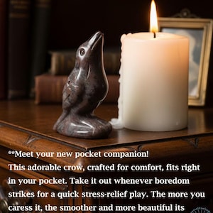 May include: A carved stone crow figurine with a candle and a framed picture. The crow is dark with lighter marbling. A white candle with a lit flame is next to the crow. Text on the image says, "Meet your new pocket companion!"