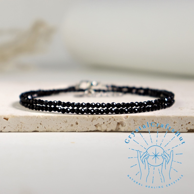 K&ouml;nnte beinhalten: Ein zartes Armband aus schwarzen Onyxperlen mit einem silbernen Verschluss. Das Armband besteht aus kleinen, runden Perlen und ist perfekt zum Schichten mit anderen Armb&auml;ndern.