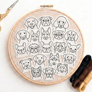 Peut inclure: Un tambour à broder en bois contenant un panneau en tissu beige avec vingt autocollants individuels en noir et blanc représentant diverses races de chiens. Les autocollants présentent des contours simples de visages et d'oreilles canins.