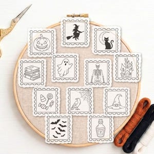 Könnte beinhalten: Ein hölzerner Stickrahmen mit einem beigen Stoffeinsatz, auf dem zwölf quadratische Aufnäher mit gezackten Rändern angebracht sind, die schwarze Strichzeichnungen von Halloween-Motiven wie Kürbis, Hexe, Katze, Geist, Skelett und Zaubertrank zeigen.