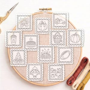 May include: A collection of twelve square, scalloped-edge paper cutouts featuring black and white line art illustrations of autumn themes, including a turkey, pumpkin, football, campfire, pie, and leaves, arranged on a wooden embroidery hoop.