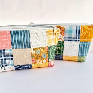 May include: Two patchwork fabric zippered pouches with a variety of colorful patterns, including floral, plaid, and geometric designs. The pouches are made of cotton fabric and have a zipper closure.
