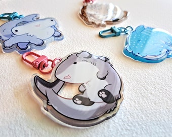 May include: Four colorful keychains featuring cartoon animal designs. Each keychain has a clear acrylic charm with a different animal, including a blue whale, a gray whale, a gray shark, and a white shark. The keychains have metal rings and colorful clasps.