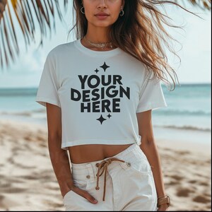 May include: White cropped t-shirt with short sleeves and the text "YOUR DESIGN HERE" in black lettering with small stars on either side.