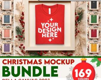May include: A red t-shirt mockup with the text "YOUR DESIGN HERE" in white. The t-shirt is framed and surrounded by Christmas greenery. The image is part of a bundle of 169 Christmas t-shirt mockups in various colors.