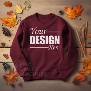 May include: A maroon sweatshirt with long sleeves and a crew neck. The sweatshirt has the text "Your Design Here" printed in white on the front.