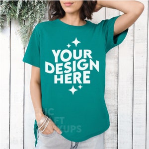 May include: A teal blue t-shirt with a white graphic that says "YOUR DESIGN HERE" with small white stars around the text.