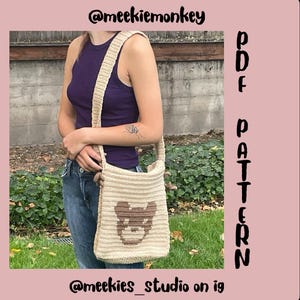 Puede incluir: Bolso de hombro de crochet beige con diseño de cara de oso de peluche marrón. El bolso tiene una correa larga y se lleva sobre el hombro. El texto en la imagen dice "@meekiemonkey", "PDF PATTERN" y "@meekies_studio on ig".