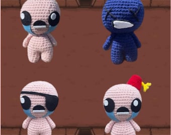 May include: Four crocheted dolls featuring round heads and small bodies. One is light pink with blue accents, one is dark blue with black X-shaped eyes, one is light pink with a black eye patch, and one is light pink with a red fez hat and yellow tassel.