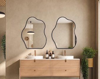 May include: A bathroom vanity with two sinks and a wooden countertop. Two black, organic-shaped mirrors hang above the sinks. A potted plant sits on the floor next to the vanity.