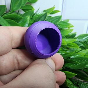 Puede incluir: Un recipiente de pl&aacute;stico morado de forma redonda con una superficie lisa y ligeramente texturizada. El recipiente tiene una abertura circular en la parte superior.