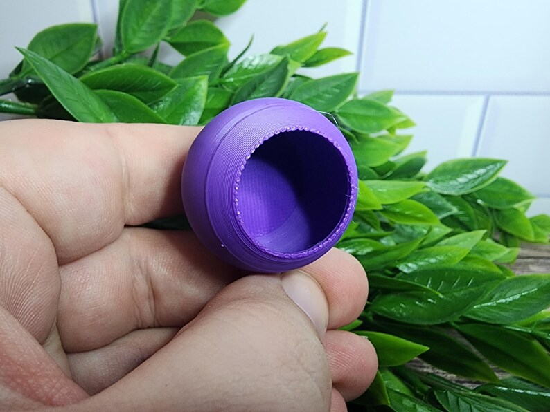 Puede incluir: Un recipiente de pl&aacute;stico morado de forma redonda con una superficie lisa y ligeramente texturizada. El recipiente tiene una abertura circular en la parte superior.