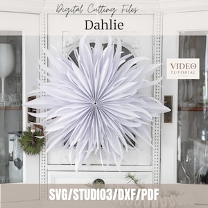 May include: A white paper dahlia flower decoration with pointed, layered petals arranged in a circular, starburst pattern. The text "Digital Cutting Files", "Dahlie", and "SVG/STUDIO3/DXF/PDF" is visible, along with a "VIDEO TUTORIAL" label.