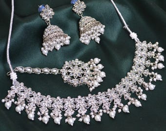 Könnte beinhalten: Ein silbernes Halsketten-Set mit floralem Design und Perlenakzenten. Das Set beinhaltet eine Halskette, Ohrringe und ein Maang Tikka.