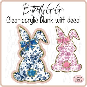May include: Two clear acrylic blank bunny shapes with floral decals. The bunny on the left has a blue and white floral pattern with a blue bow. The bunny on the right has a pink and white floral pattern with a pink bow. The text "Butterfly Gigi" and "Clear acrylic blank with decal" is at the top of the image. The text "No Badge Reel included" is at the bottom of the image.