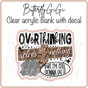 May include: A clear acrylic blank with a decal featuring the text "OVERTHINKING solves nothing BUT I'M STILL GONNA DO IT." The design includes a leopard print lightning bolt, stars, and a checkered pattern.