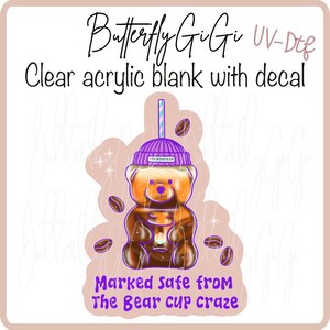 May include: A clear acrylic blank with a decal featuring a bear-shaped coffee cup design. The bear is brown with a purple beanie and a striped straw. The text reads "Butterfly GiGi", "Clear acrylic blank with decal", and "Marked safe from The Bear cup craze."
