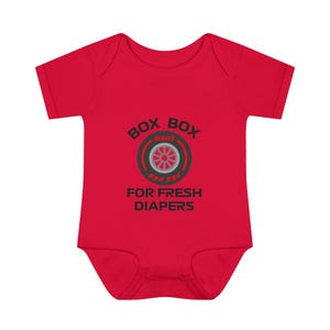 Könnte beinhalten: Roter Baby Strampler mit einer schwarzen und grauen Grafik, auf der "Box Box for Fresh Diapers" steht, und einem roten Reifen mit einer grauen Felge.