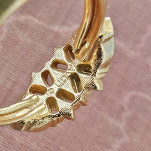 May include: A gold-toned ring featuring a textured, leaf-like design with a series of open, oval-shaped cutouts along the band. The metal surface displays a fine, brushed finish, and the word LION is clearly stamped on the inner side of the band.
