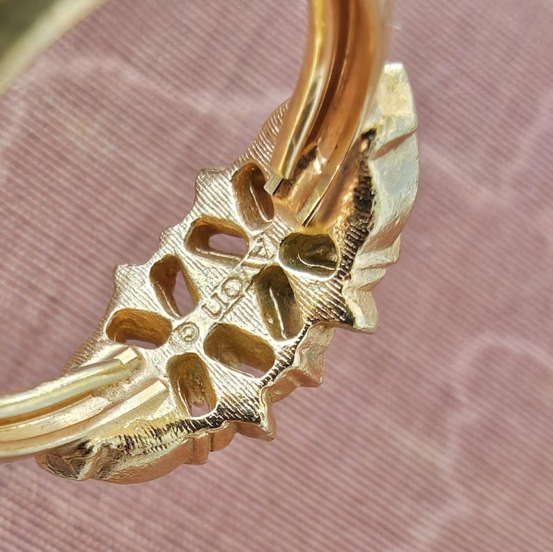 May include: A gold-toned ring featuring a textured, leaf-like design with a series of open, oval-shaped cutouts along the band. The metal surface displays a fine, brushed finish, and the word LION is clearly stamped on the inner side of the band.
