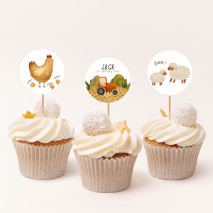 Puede incluir: Tres cupcakes decorados con adornos temáticos de animales de granja. Los adornos representan una gallina con pollitos, un tractor con el texto "JACK cumple dos años", y dos ovejas con el texto "¡bee!"