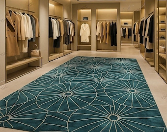 May include: A teal and white patterned rug dominates the foreground of a clothing store. The rug features a repeating circular design with radiating lines. Clothing racks with various garments are visible in the background, along with display shelves.