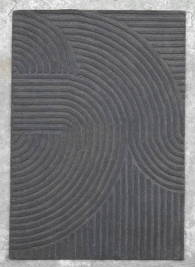 May include: A black and grey area rug with a geometric pattern of curved lines.