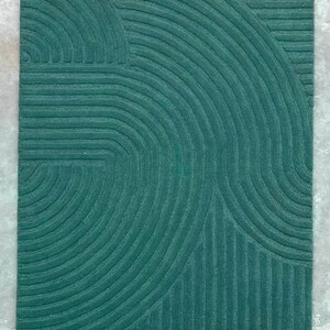 May include: A teal green rug with a geometric pattern of curved lines and stripes.