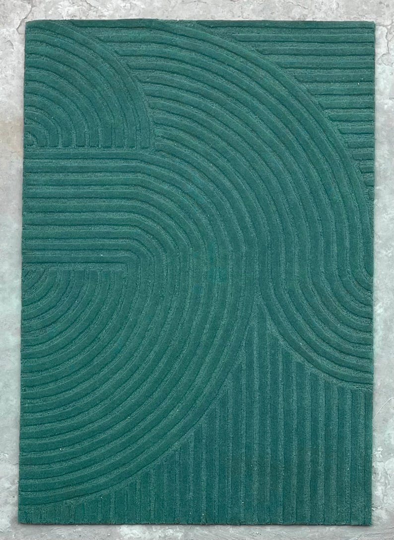 May include: A teal green rug with a geometric pattern of curved lines and stripes.