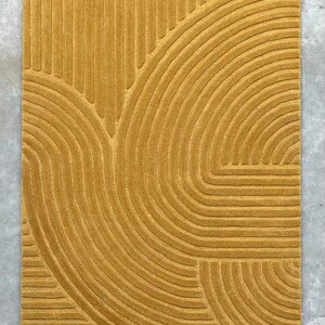 May include: A mustard yellow rug with a geometric pattern of curved lines.