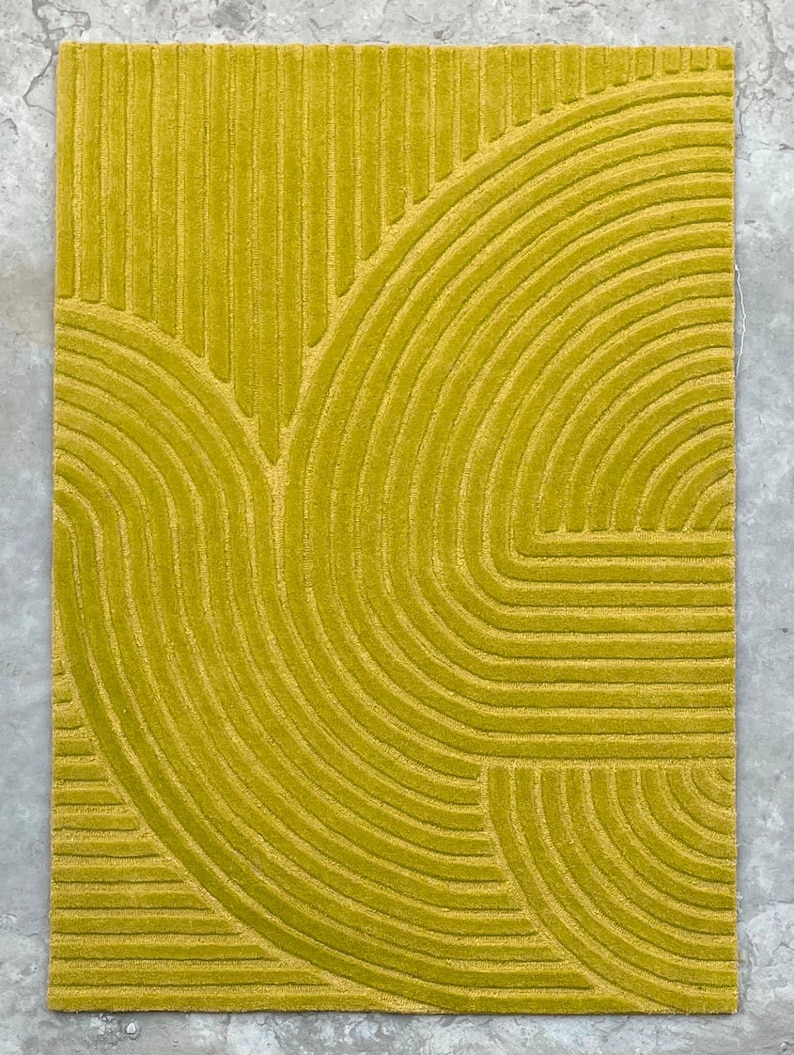 May include: A yellow rug with a geometric pattern of curved lines. The rug has a textured surface and a modern design.