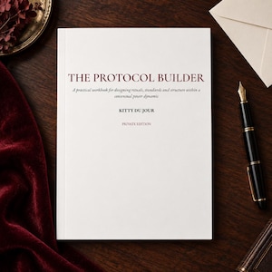 Op de afbeelding: Een wit werkboek getiteld THE PROTOCOL BUILDER door Kitty Du Jour, met de ondertitel A practical workbook for designing rituals, standards and structure within a consensual power dynamic en de tekst PRIVATE EDITION op de omslag.