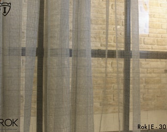 May include: A close-up of a sheer, light grey curtain with a grid pattern. The curtain is hanging in front of a window with a brick wall behind it. The text "Rok|E - 301" is visible in the bottom right corner of the image.
