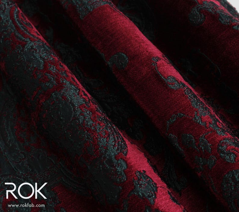 May include: Close-up of a fabric with a damask pattern. The fabric is a deep burgundy color with a black, ornate design. The fabric is folded, showing the texture and depth of the material. The logo "ROK" and website address are visible in the bottom left corner.