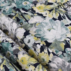 May include: Close-up of floral fabric with a dark navy background. The fabric features large white, light blue, and yellow flowers with green leaves. The text "ROK" and website address are visible in the upper right corner.