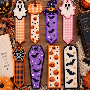 Könnte beinhalten: Acht rechteckige und sargförmige Lesezeichen mit Halloween-Motiven, darunter weiße und rosa Geister, orangefarbene Kürbisse, violette Hexenhüte, schwarze Fledermäuse, Sterne, Monde und Spinnennetze, alle mit genähten Rändern und runden Löchern oben.