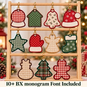 May include: A wooden display rack holding eleven fabric Christmas ornaments in various shapes including a snow globe, house, bell, Santa hat, star, mitten, angel, stocking, snowman, tree, and gingerbread man with the text 10+ BX monogram Font Included.