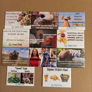 Könnte beinhalten: Ein Satz von neun bunten Magneten mit humorvollen Sprüchen über Essen und Kochen. Die Magnete zeigen Illustrationen von einem Kaninchen, einem Roten Panda, einem Murmeltier, einer Person, die Cornflakes isst, einer Person, die ein Frühstücks-Sandwich isst, einen Teller Pommes, ein Glas Bier, einen Salat und einen Teller Pizza.