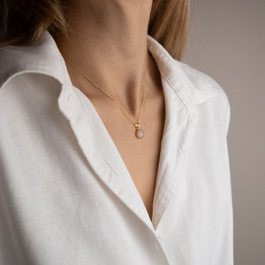 Model facing towards the light, highlighting the play of light on the 14K solid gold, circle shape Rose Quartz necklace, showcasing its unique reflections.