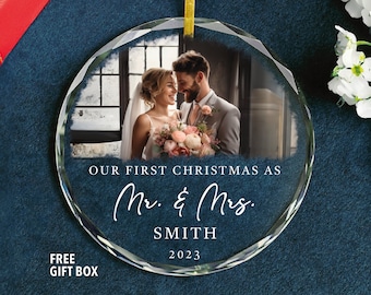 May include: A clear glass Christmas ornament with a photo of a couple in their wedding attire. The ornament has the text "Our First Christmas as Mr. & Mrs. SMITH 2023" printed on it.