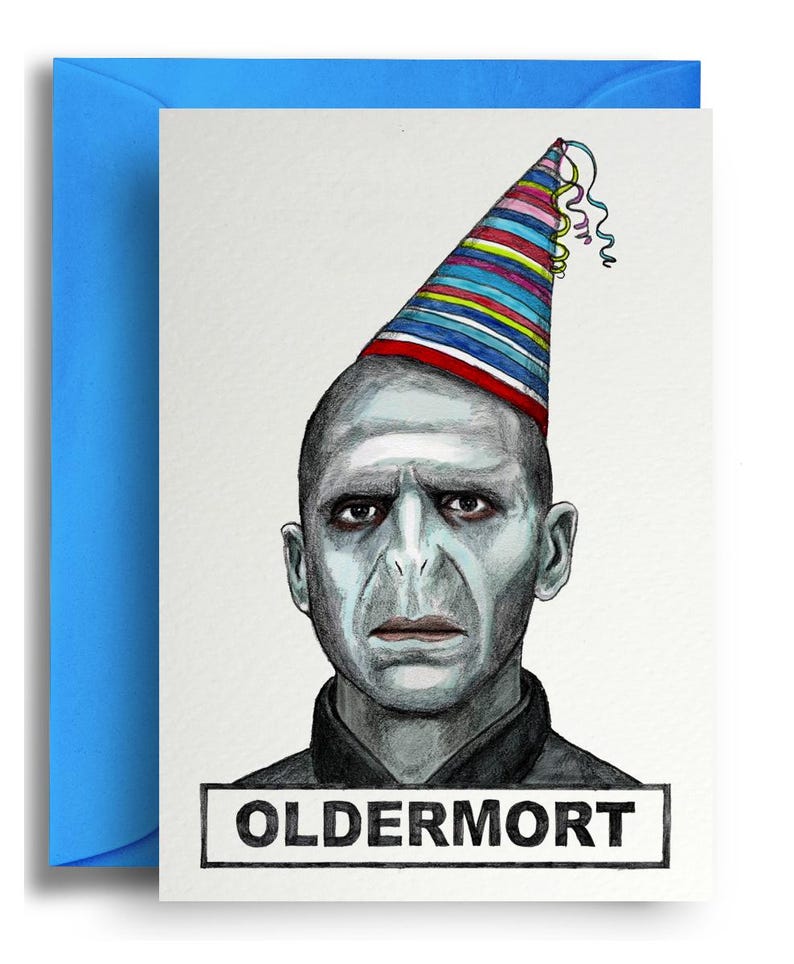 May include: Greeting card with a portrait of a pale-skinned man wearing a party hat with colorful stripes and streamers. The card has the word "OLDERMORT" in a rectangular box at the bottom. The card is inside a blue envelope.