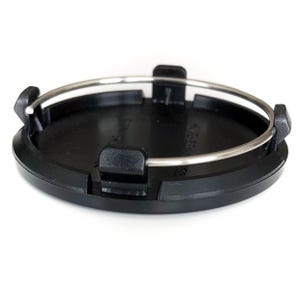 Può includere: Un coprimozzo nero con un anello metallico argentato e tre clip nere. Il coprimozzo è circolare e poggia su uno sfondo bianco. Il coprimozzo è un ricambio auto.