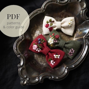 Pode incluir: Três gravatas borboleta de tecido bordado em creme, bordô e verde oliva, cada uma com desenhos florais. As gravatas borboleta estão dispostas em uma bandeja de prata decorativa. A imagem também inclui o texto "PDF patterns & color guide."